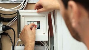 Persona revisando un cuadro eléctrico en una vivienda para asegurar la protección de la instalación ante fallos y prevenir sobrecargas eléctricas.