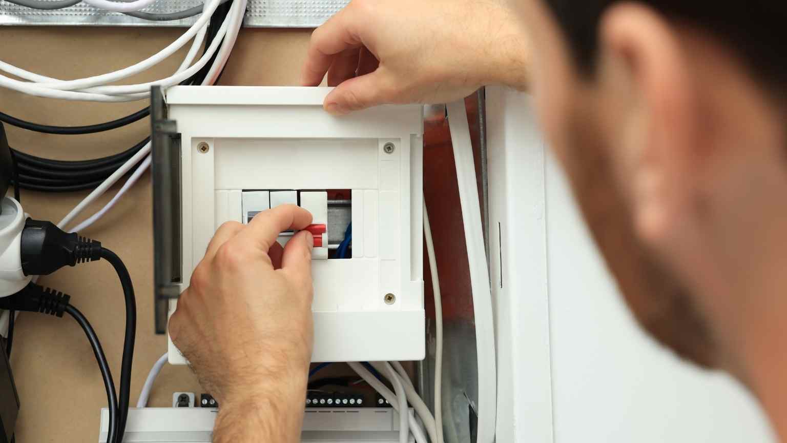 Persona revisando un cuadro eléctrico en una vivienda para asegurar la protección de la instalación ante fallos y prevenir sobrecargas eléctricas.