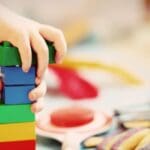 Niño pequeño jugando con bloques de construcción sobre el suelo en casa