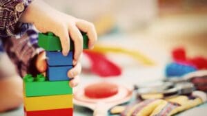 Niño pequeño jugando con bloques de construcción sobre el suelo en casa