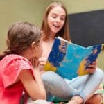 Niños escuchando un cuento leído por una adulta, actividad que estimula el lenguaje infantil de forma natural y divertida en un entorno educativo