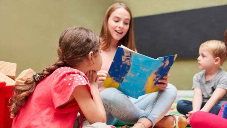 Niños escuchando un cuento leído por una adulta, actividad que estimula el lenguaje infantil de forma natural y divertida en un entorno educativo