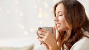 Mujer joven tomando una infusión natural en un entorno tranquilo, representando el bienestar femenino en cada etapa del ciclo.