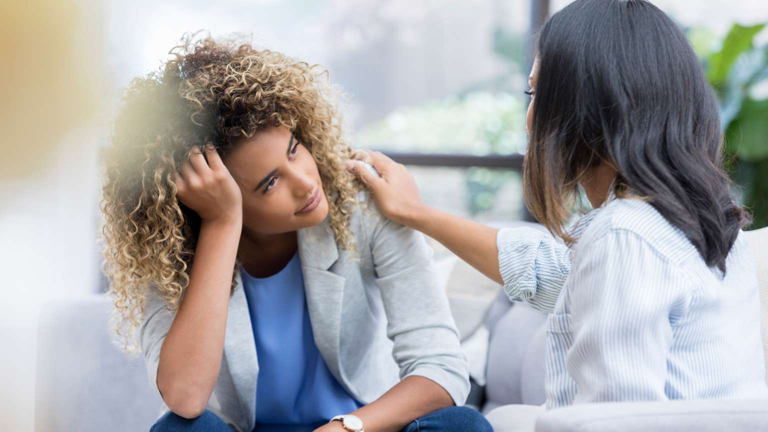 Mujer visiblemente agotada emocionalmente recibiendo apoyo de otra mujer, posible terapeuta, en un entorno que representa la atención integral de un centro médico.