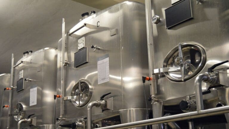 Depósitos de acero inoxidable para aceite en planta de producción, con acabado pulido y equipamiento industrial para conservación óptima del producto.