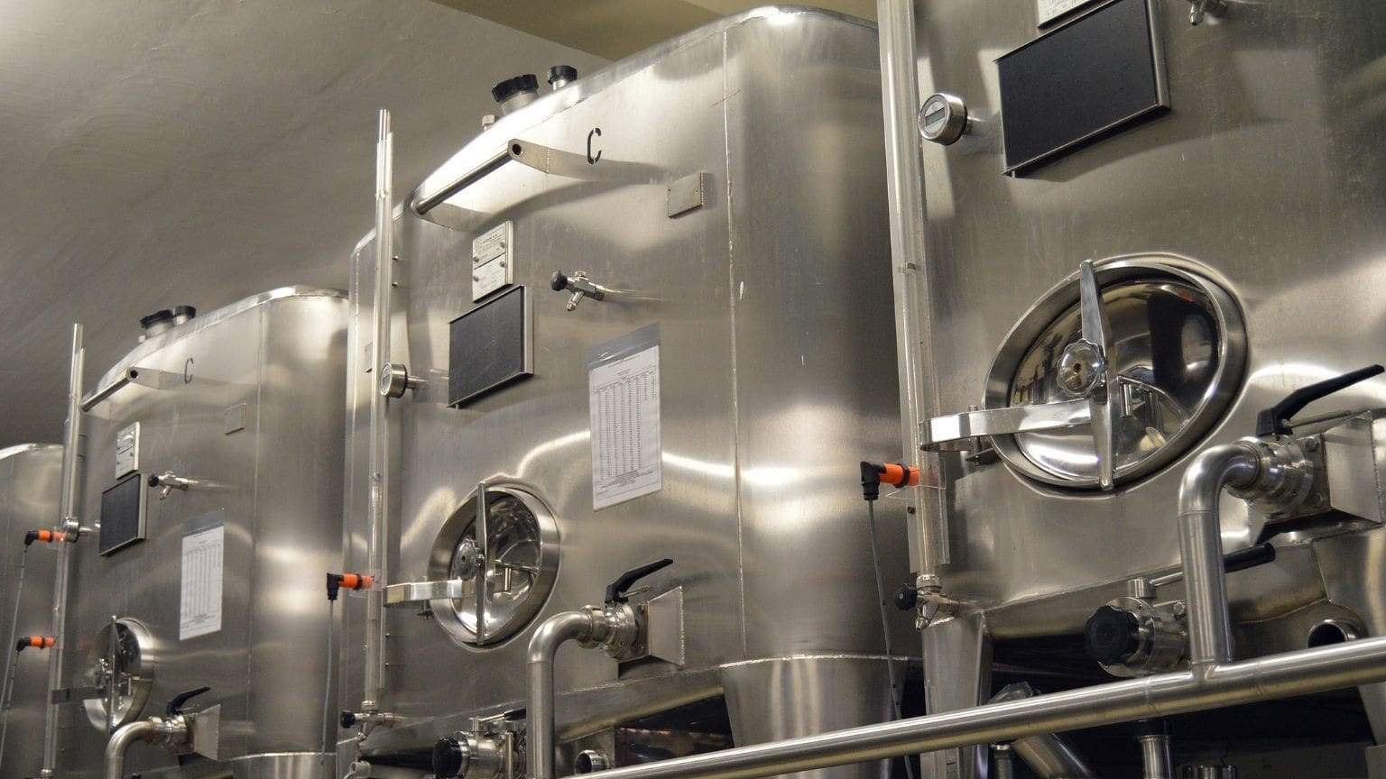 Depósitos de acero inoxidable para aceite en planta de producción, con acabado pulido y equipamiento industrial para conservación óptima del producto.