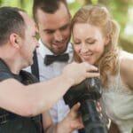 Pareja revisando portafolio con fotógrafo de bodas profesional antes de contratar servicios de fotografía y vídeo para reportaje de boda natural