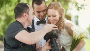 Pareja revisando portafolio con fotógrafo de bodas profesional antes de contratar servicios de fotografía y vídeo para reportaje de boda natural