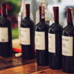 Botella de vinos naturales sobre mesa de madera con fondo de viñedo ecológico