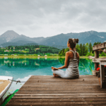 Mujer meditando frente a un lago en plena naturaleza