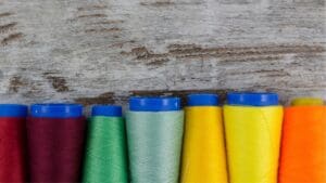Bobinas de hilos de coser de distintos colores y grosores organizadas sobre una mesa, mostrando opciones para costura profesional y creativa.