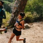 Persona entrenando trail running en montaña con equipo técnico en entorno natural