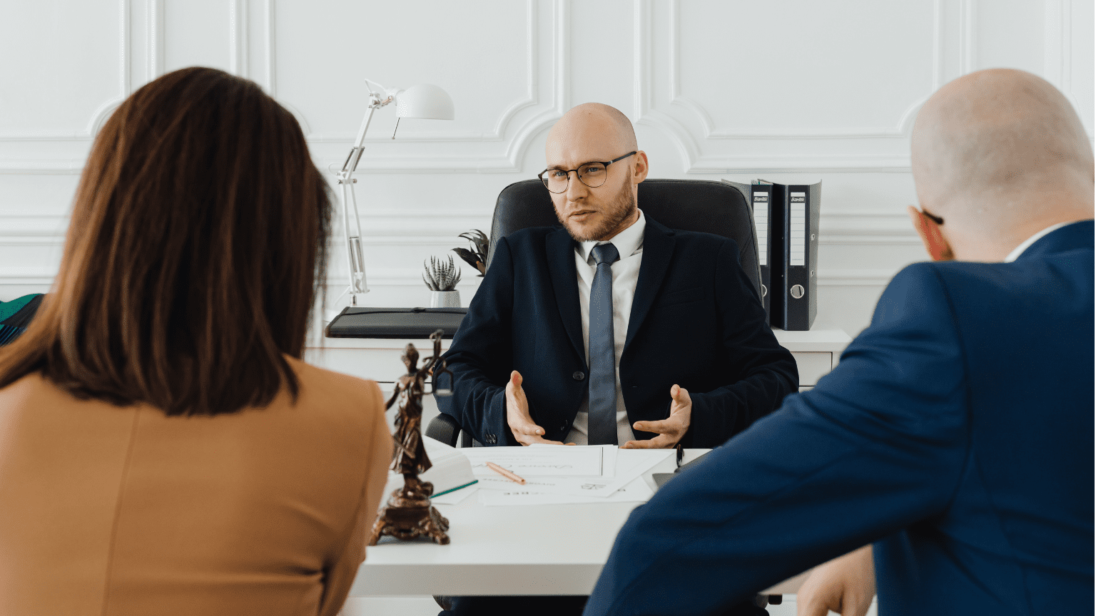Abogado asesorando a una pareja en una consulta jurídica profesional.