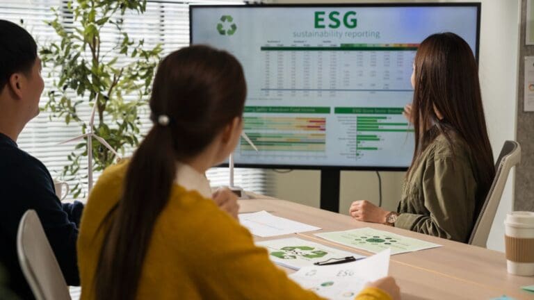 Equipo de consultoría ambiental analizando informe de sostenibilidad ESG en oficina, con gráficos y documentación técnica sobre residuos.