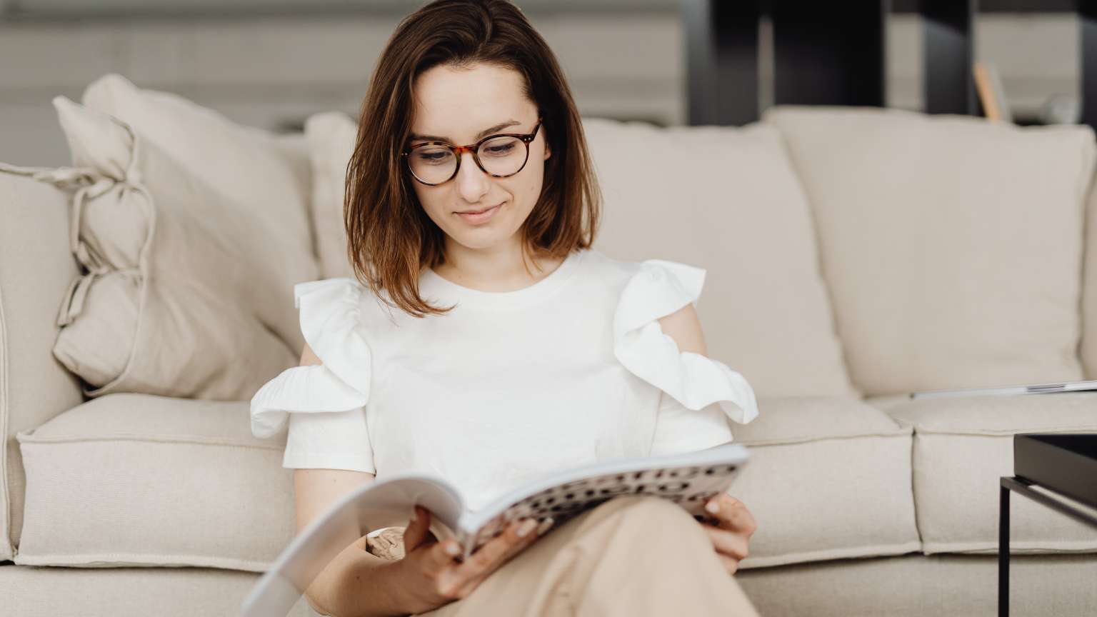Mujer sentada leyendo en una sala tranquila mientras usa gafas de lectura con estilo