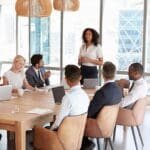 Equipo de oficina desmotivado y desconectado durante una reunión, reflejando una cultura empresarial tensa y poco colaborativa.