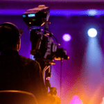 Técnico de cámara grabando en un set con iluminación de colores durante una producción audiovisual profesional.