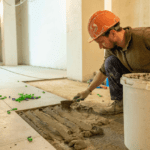Trabajador colocando suelo durante reforma integral de vivienda