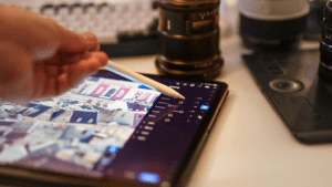 Edición creativa de imagen en tablet con stylus y herramientas de diseño gráfico profesional sobre escritorio.