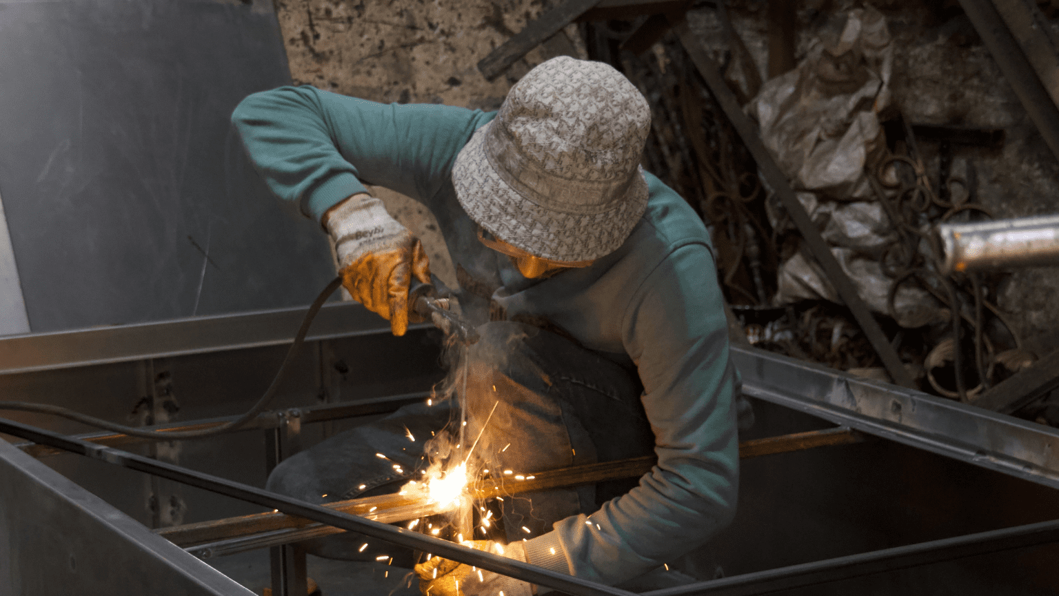 Soldador profesional trabajando en la fabricación de estructuras metálicas con técnicas de soldadura por arco en taller industrial.