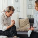 Mujer sentada con expresión triste reflexionando sobre su relación tóxica, en un espacio tranquilo que transmite necesidad de apoyo emocional y sanación