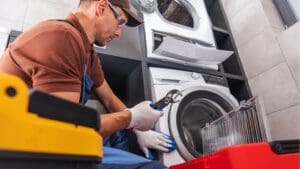 Técnico revisando lavadora que no desagua en casa, reparación de electrodomésticos en Tarragona.