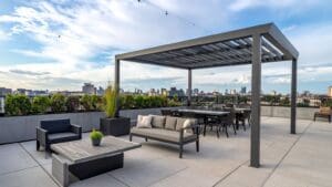 Pérgola bioclimática moderna instalada en una terraza con mobiliario de exterior, ideal para proteger del sol y la lluvia durante todo el año.