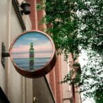 Cartel publicitario metálico de alta calidad instalado en fachada comercial, ideal para destacar una marca con imagen profesional y duradera