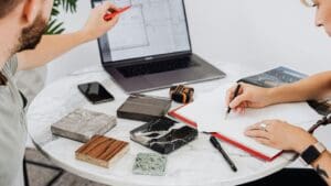Selección de materiales y acabados para proyecto arquitectónico sobre mesa de trabajo, con planos y muestras visibles.
