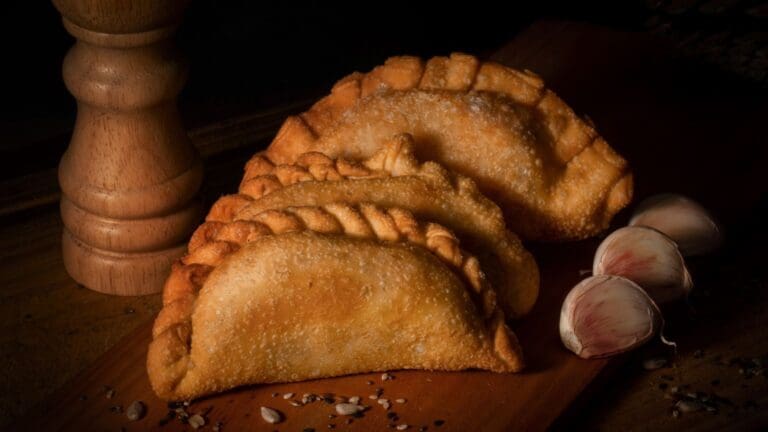 Empanadas argentinas caseras con masa dorada y repulgue artesanal servidas en mesa rústica junto a salsa criolla tradicional