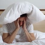 Persona con dificultad para dormir y síntomas neurológicos visibles, reflejando fatiga, dolor de cabeza y necesidad de atención médica especializada