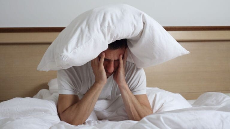 Persona con dificultad para dormir y síntomas neurológicos visibles, reflejando fatiga, dolor de cabeza y necesidad de atención médica especializada