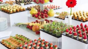 Mesa de catering variado con opciones dulces, saladas, veganas y sin gluten para diferentes tipos de invitados en eventos