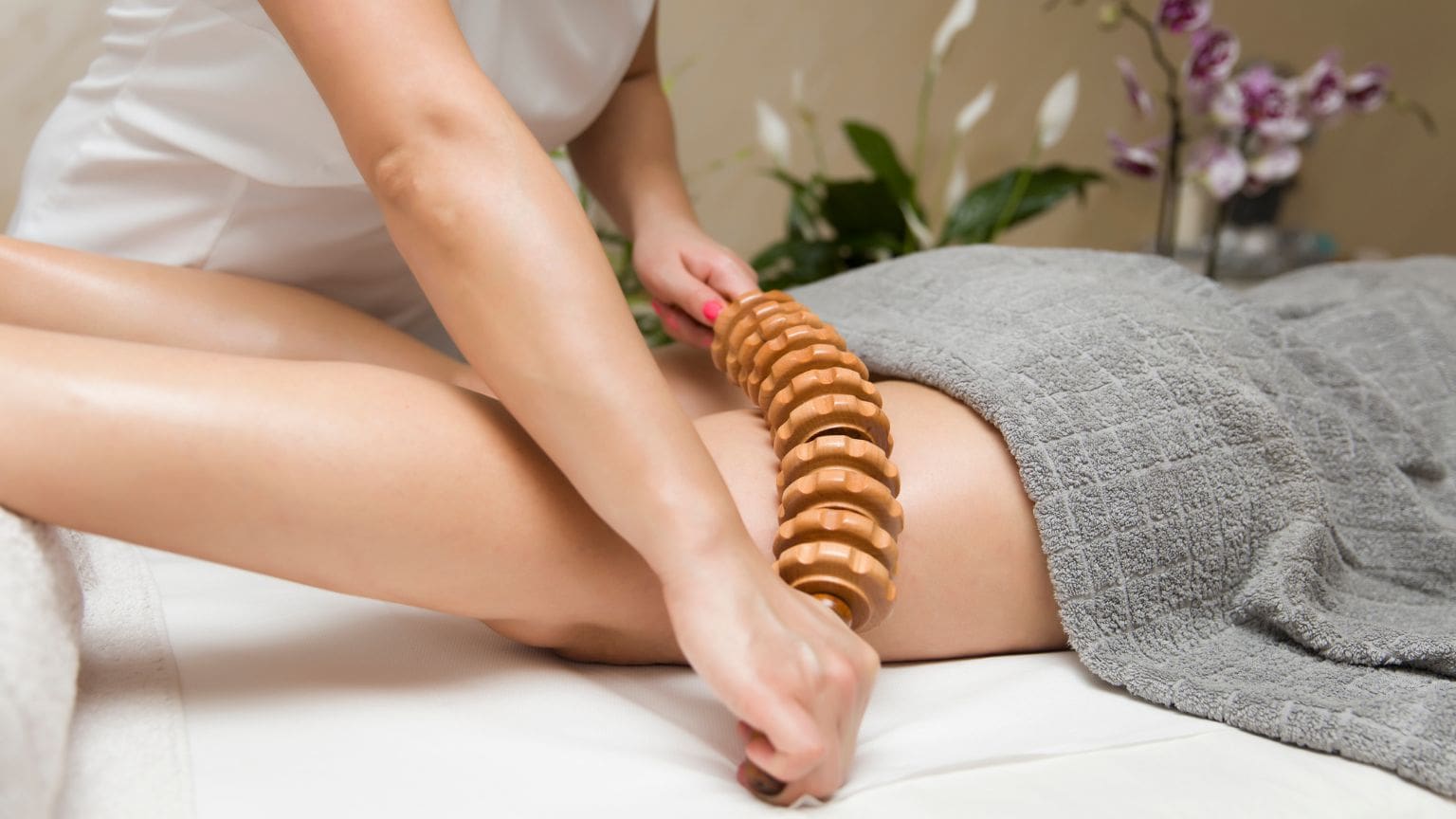 Mujer recibiendo maderoterapia corporal en centro de estética, masaje con rodillos de madera para reducir celulitis y mejorar la textura de la piel