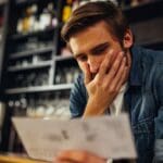 Empleado preocupado revisando su nómina por impago o retraso de salario en el entorno laboral