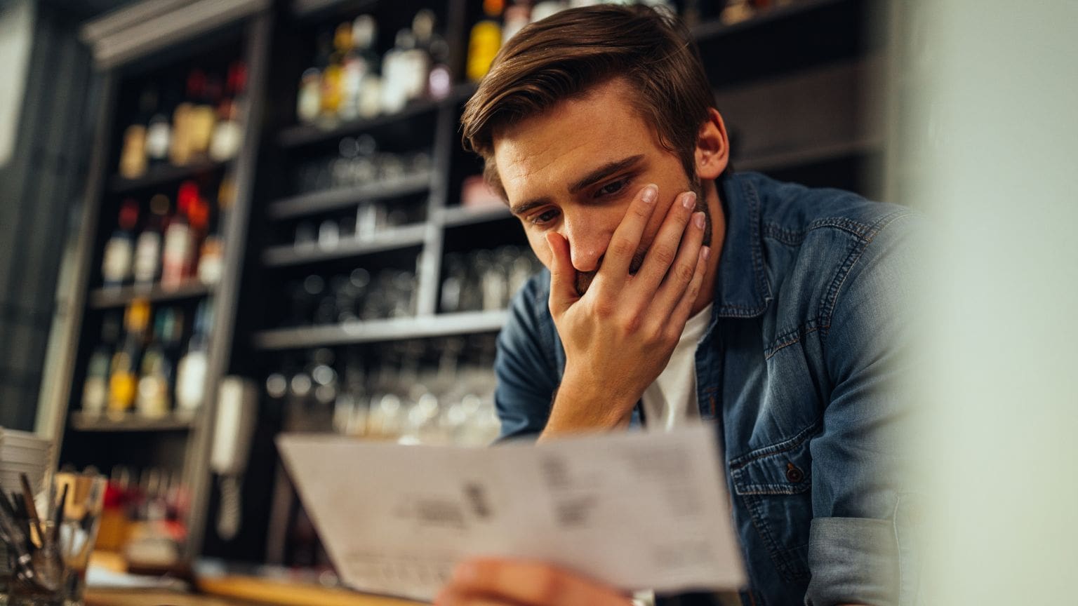 Empleado preocupado revisando su nómina por impago o retraso de salario en el entorno laboral