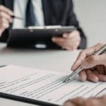 Empresarios firmando contratos mercantiles en reunión profesional