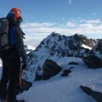 Turismo en Granada desde la alta montaña con montañista contemplando las cumbres nevadas de Sierra Nevada