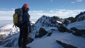 Turismo en Granada desde la alta montaña con montañista contemplando las cumbres nevadas de Sierra Nevada