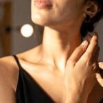 perfumes unisex aplicados en el cuello con frasco elegante en un entorno cálido y sofisticado