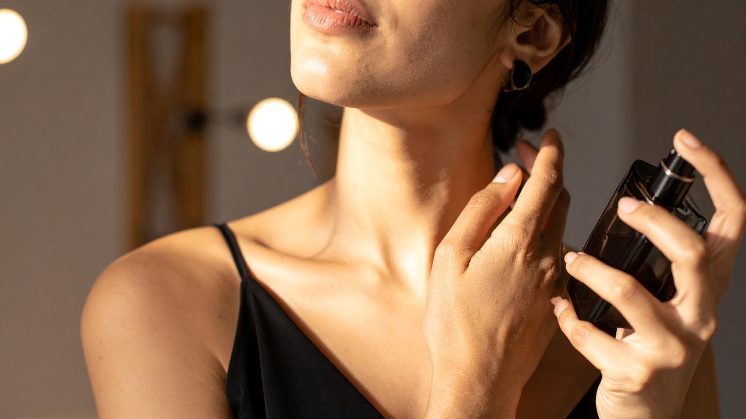 perfumes unisex aplicados en el cuello con frasco elegante en un entorno cálido y sofisticado