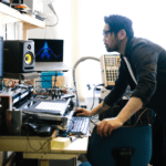 Productor musical trabajando en su estudio con equipos electrónicos.