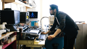 Productor musical trabajando en su estudio con equipos electrónicos.