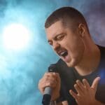 Cantante con tensión en el cuello mientras canta por una mala postura corporal.