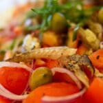 Ensalada fresca con tomate, aceitunas, cebolla morada y pescado típica de un restaurante mediterráneo tradicional